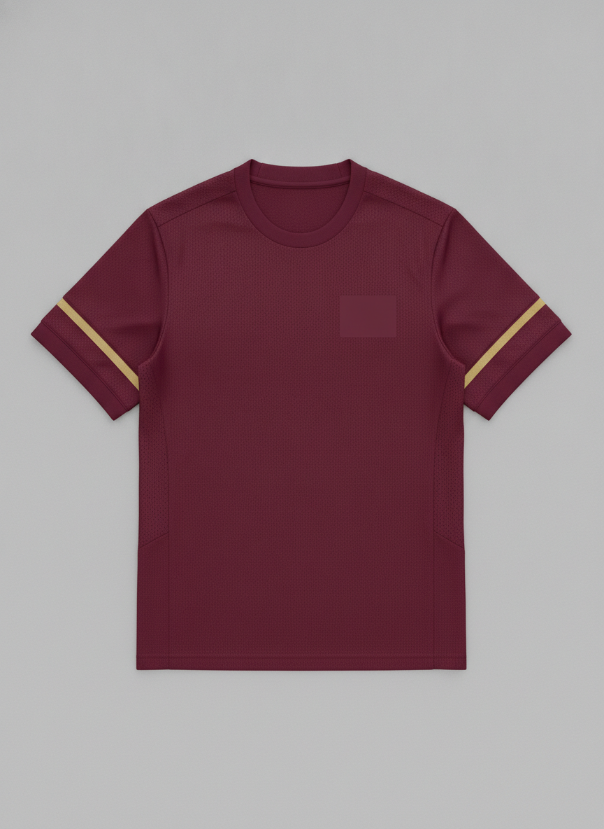 AI jersey design generator example — flat front view of a deep burgundy football shirt with thin gold sleeve stripes, a blank crest patch on the left chest and a ribbed collar, on a pale grey background