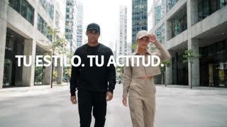 Video publicitario urbano, texto a video, duración máxima 8 segundos, estilo cinematográfico realista. Escena en una calle moderna de ciudad con edificios altos, concreto y cristal, ambiente streetwear premium.

Aparecen dos modelos jóvenes caminando hacia la cámara. El hombre viste outfit negro completo, tenis blancos y gorra negra lisa de 6 paneles con visera curva. La mujer viste outfit beige tipo cargo, tenis blancos y gorra beige lisa de 6 paneles con visera curva.

Ambos modelan principalmente las gorras mientras caminan. El hombre toca suavemente la visera y la mujer acomoda su gorra y gira ligeramente el rostro para mostrarla de perfil. Incluir breves primeros planos de las gorras para resaltar forma, textura y costuras.

Importante: la gorra negra del modelo hombre debe permanecer puesta durante todo el video, en todas las escenas y todos los cambios de plano. Nunca debe desaparecer, quitarse ni cambiarse. En la última escena, el modelo hombre debe seguir usando claramente la gorra negra.

Movimientos totalmente naturales, fluidos y humanos, sin rigidez, deformaciones ni movimientos robóticos. Cámara suave tipo comercial de moda.

Texto en pantalla: “TU ESTILO. TU ACTITUD.” y al final “ENCUENTRA TU COLOR”. Ortografía extremadamente estricta: sin errores, letras deformadas ni palabras inventadas.
