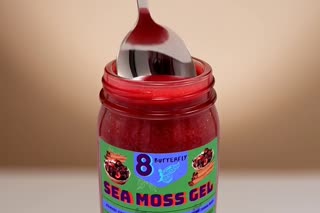 Show the exact Sea Moss Gel product from the uploaded reference image. Close-up macro shot of a spoon dipping into the Sea Moss Gel and slowly lifting one spoonful from the jar. Focus on the smooth texture of the gel. The jar remains visible in the background. Realistic food photography. Slow motion. Cinematic lighting. Do not change the jar, label, logo, or product appearance. No text. No additional products.