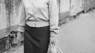 Créer une vidéo montrant cette jeune femme marcher dans la rue. La caméra la suit en pivotant vers la gauche, la jeune est de face au début de la vidéo, adresse un léger sourire en passant au niveau d la caméra puis est de dos en fin des vidéo. On entend simplement le bruit de ses pas.