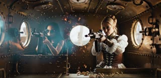 Interior of the armored car, all brass with portholes for windows as seen in the reference mage.  The blonde woman should look exactly as she looks in the reference image.  The girl with black hair should have her hair piled high like a Gibson Girl and wear very old-fashioned round wire rimmed sunglasses. Her clothing should be blue in color, pseudo-Edwardian. Both women are firing machine rifles through the portholes of the armored automobile and not straight ahead. The car has round windows or portholes and the women are firing through those, in a cinematic scene with professional lighting, shallow depth of field, and movie-quality visual effects

 in a cinematic scene with professional lighting, shallow depth of field, and movie-quality visual effects