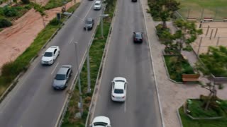 The scene moves at a higher speed and with close zoom throughout the entire space, from beginning to end.
Maintain the exact design and characteristics of the image; do not make any changes to the current design.

Vehicles travel along the road, the right lane going in one direction, the left lane going in the opposite direction, respecting traffic laws, the direction of the road, and a safe distance between them. Tree foliage with slight wind movement. in a cinematic scene with professional lighting, shallow depth of field, and movie-quality visual effects