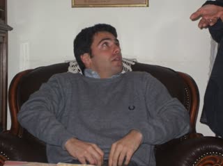 Create a short, highly realistic video animation from this photograph. Preserve the exact identity, facial features, proportions, and original facial expression of the person. His expression must remain exactly as in the image: slightly confused, uncertain, and a bit awkward — do not modify, enhance, or reinterpret the expression in any way.

Strict expression lock: no smiling, no added emotion, no exaggeration, no change in eye shape, gaze direction, or mouth position. The eyes must keep the