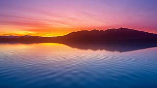 A serene mountain lake at sunset with gentle ripples