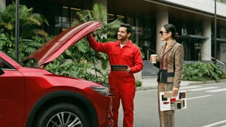 The scene is in slow motion; the people in the scene talk a little, smile, and the man in red is seen receiving his tablet and looking at the car's engine.